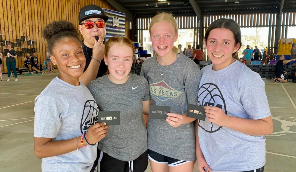 4 girls (and ref) posing with prizes post basketball tournament