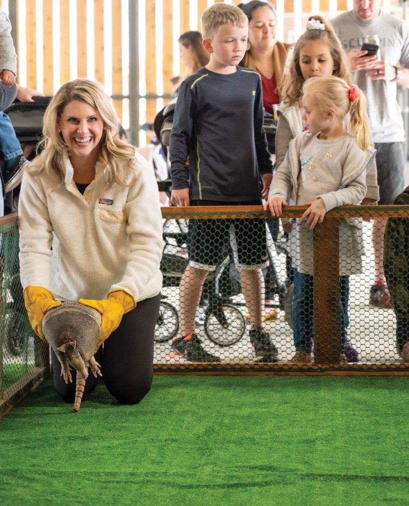 woman laughing holding an armadillo before a race