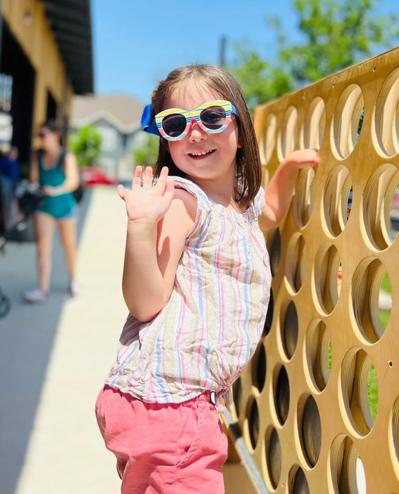 little girl with sunglasses playing gigantic Connect Four game